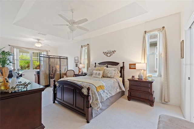 bedroom with ceiling fan, a raised ceiling, and light carpet