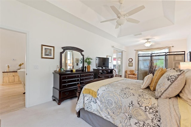 carpeted bedroom with a raised ceiling and ceiling fan