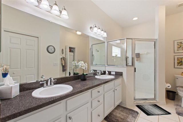 bathroom featuring tile patterned floors, toilet, a shower with shower door, and vanity