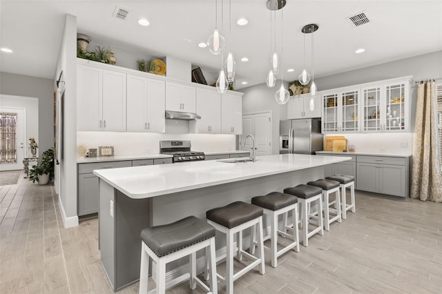 kitchen with stainless steel appliances, a kitchen bar, sink, and a center island with sink