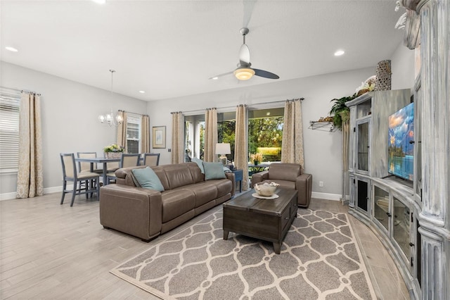 living room with ceiling fan with notable chandelier and light wood-type flooring