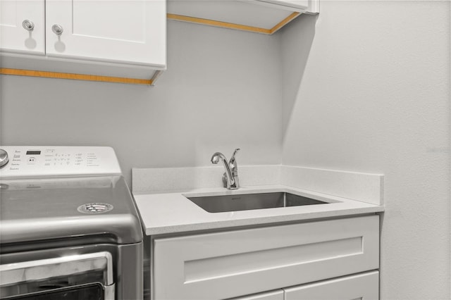 laundry area with cabinets, washer / clothes dryer, and sink