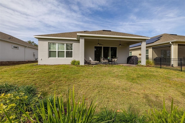 back of house with a yard, a patio area, ceiling fan, and solar panels