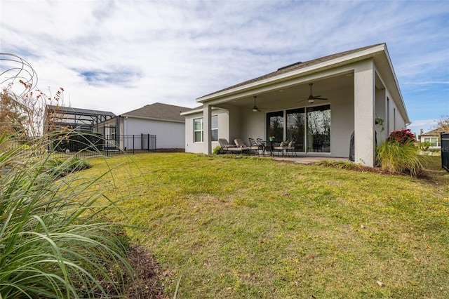 back of property with a yard, ceiling fan, and a patio area