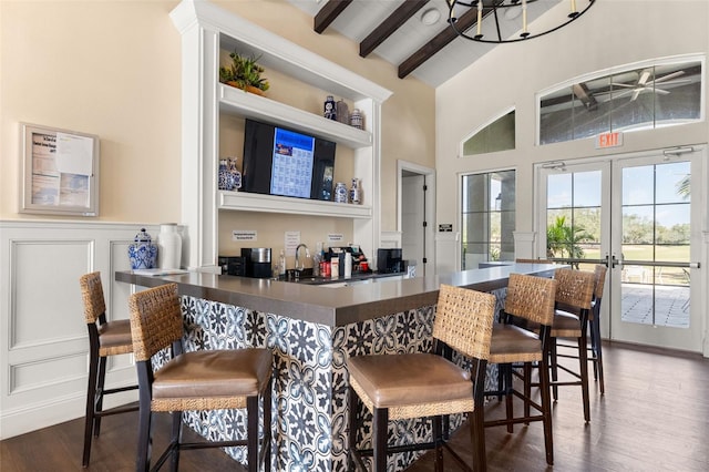 bar featuring dark wood-type flooring, beam ceiling, sink, and french doors