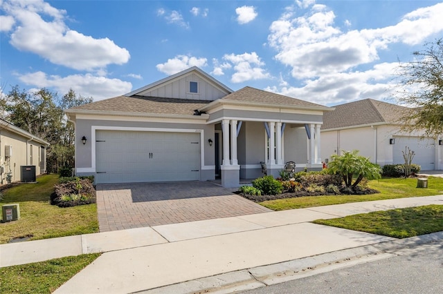 view of front of property featuring a garage, central AC, a front yard, and covered porch