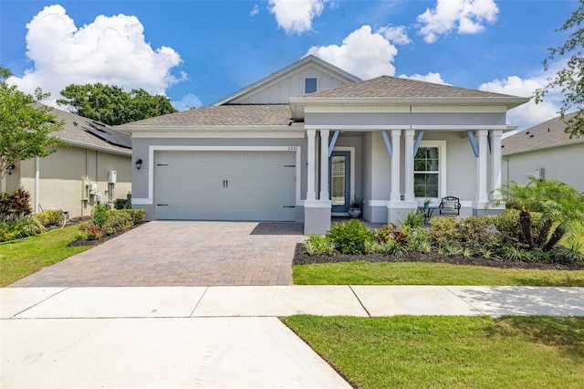 2051 Flora Pass Pl, Kissimmee, FL 34747 - view of front facade with covered porch, an attached garage, stucco siding, a front yard, and decorative driveway