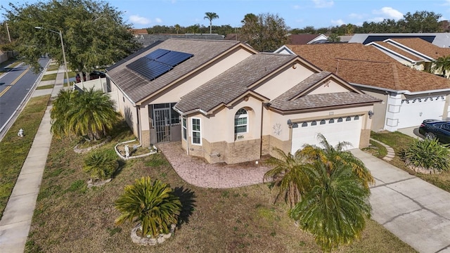 view of front of property with a garage, solar panels, and a front lawn