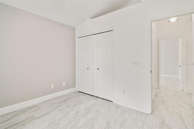 unfurnished bedroom with a closet and lofted ceiling