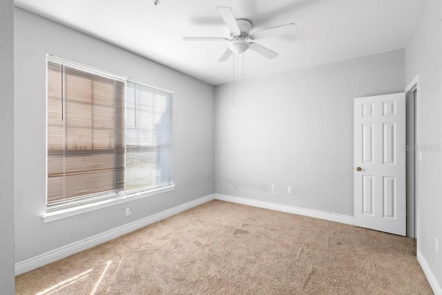 carpeted spare room featuring ceiling fan