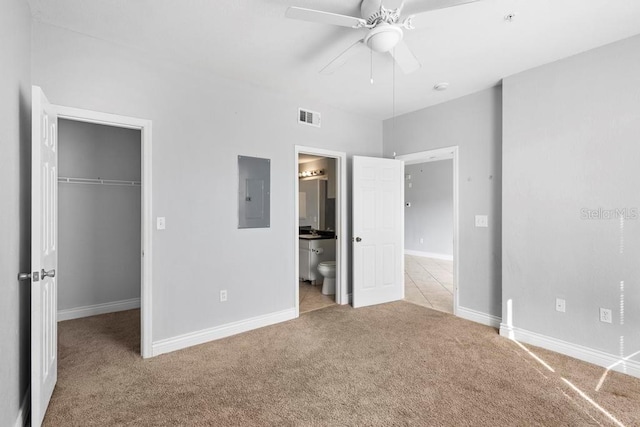 unfurnished bedroom featuring ensuite bathroom, electric panel, a closet, and a walk in closet