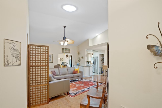 living room featuring light hardwood / wood-style flooring, vaulted ceiling, and ceiling fan