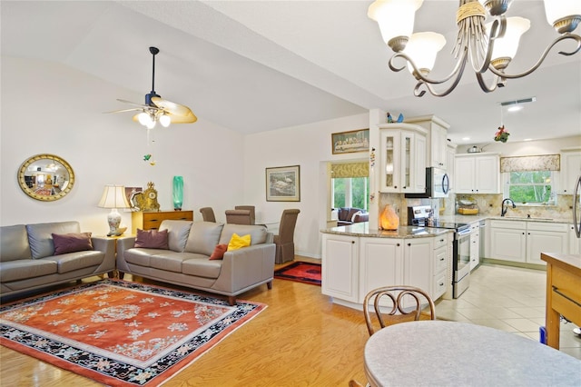 living room featuring lofted ceiling, sink, ceiling fan with notable chandelier, and light hardwood / wood-style flooring