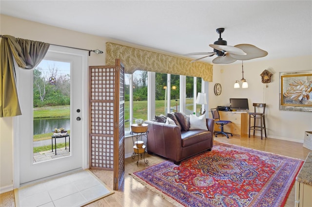 living room with plenty of natural light, light hardwood / wood-style floors, ceiling fan, and a water view