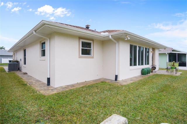 view of side of home with central AC unit, a patio area, and a lawn