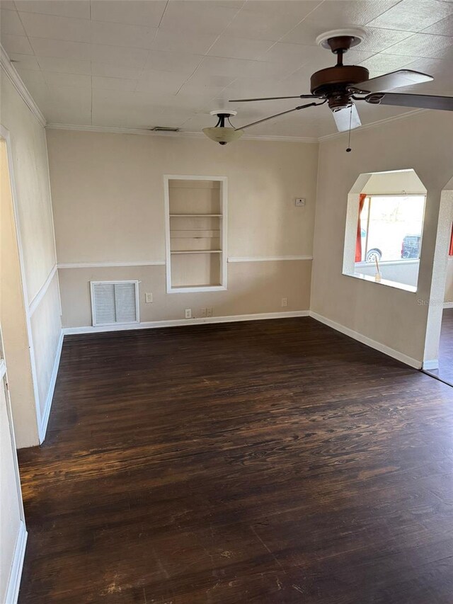 spare room featuring built in shelves, ceiling fan, ornamental molding, and dark hardwood / wood-style floors