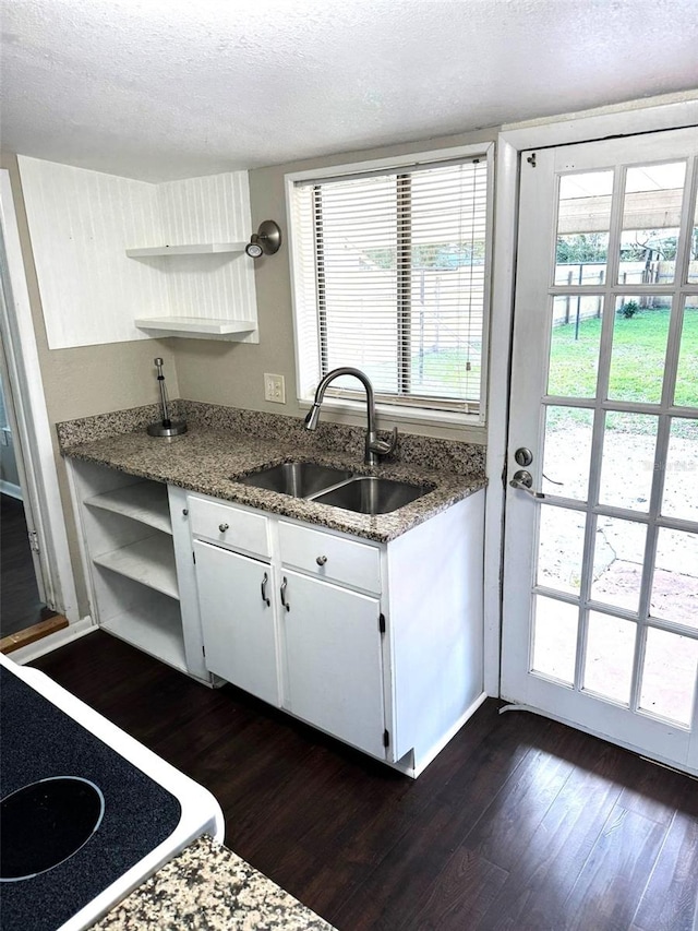 kitchen featuring white cabinetry, sink, dark stone countertops, dark hardwood / wood-style flooring, and a textured ceiling