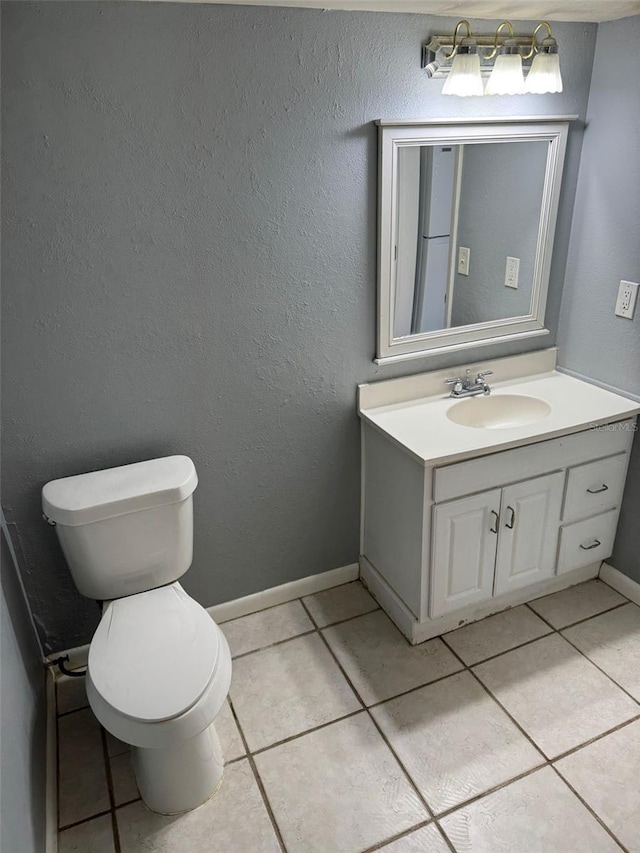 half bath featuring toilet, tile patterned floors, baseboards, and vanity