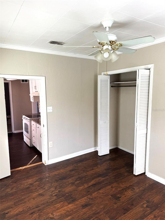 unfurnished bedroom featuring crown molding, dark wood-type flooring, a closet, and ceiling fan