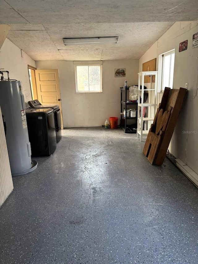 interior space with washing machine and dryer, water heater, and a textured ceiling