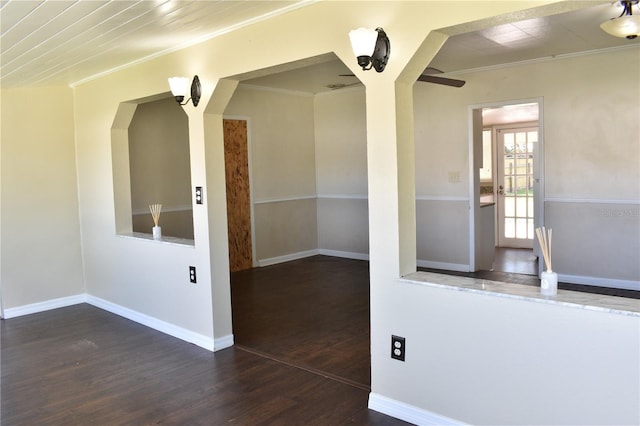 spare room featuring crown molding, baseboards, and wood finished floors