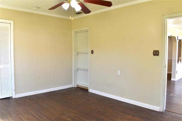 spare room featuring baseboards, ornamental molding, ceiling fan, and dark wood-type flooring