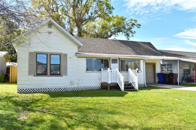 view of front facade with an attached garage, roof with shingles, concrete driveway, and a front yard