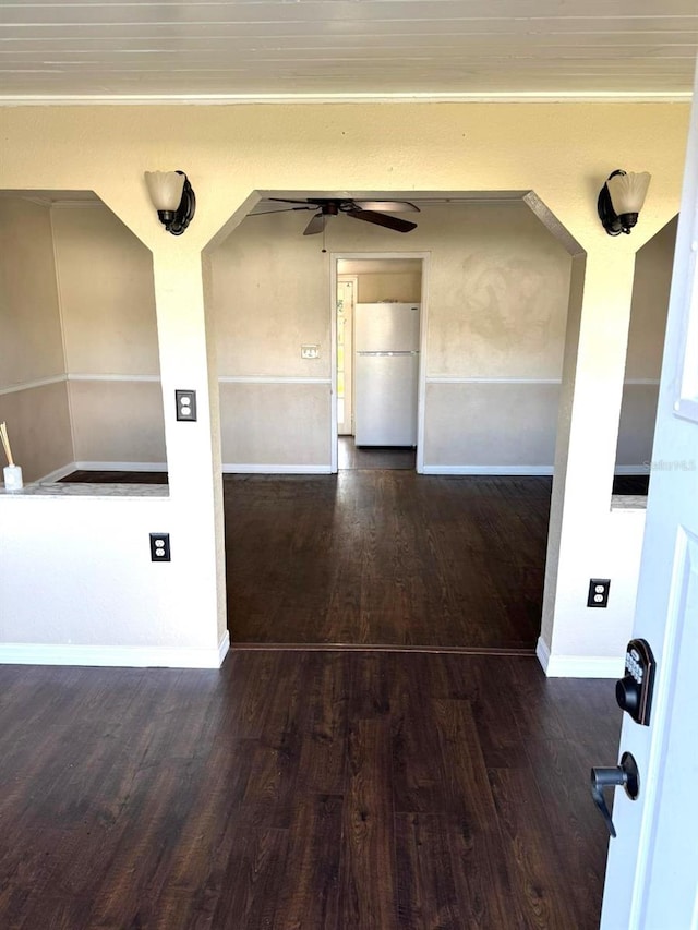 empty room with crown molding, ceiling fan, baseboards, and wood finished floors