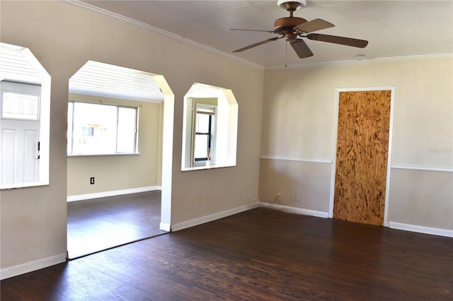 spare room with baseboards, ornamental molding, ceiling fan, and wood finished floors