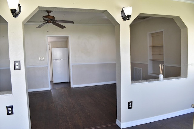 unfurnished room featuring arched walkways, ceiling fan, baseboards, and wood finished floors