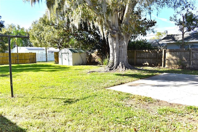 view of yard featuring an outbuilding, a fenced backyard, a patio, and a storage unit