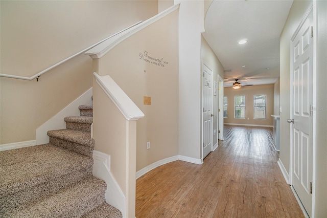 stairway with hardwood / wood-style floors and ceiling fan