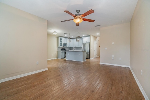 unfurnished living room featuring ceiling fan, sink, and light wood-type flooring