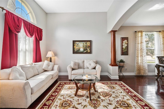 living room featuring decorative columns and dark hardwood / wood-style flooring