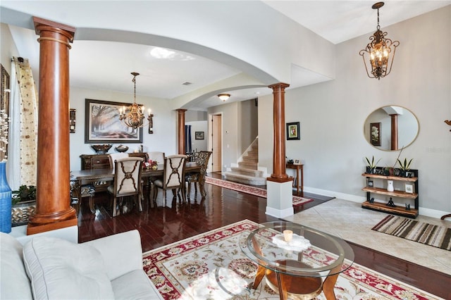 living room with a notable chandelier, hardwood / wood-style flooring, and decorative columns