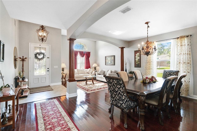 dining room with decorative columns, dark hardwood / wood-style flooring, and an inviting chandelier