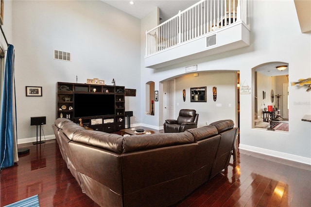 living room with dark hardwood / wood-style flooring and a towering ceiling