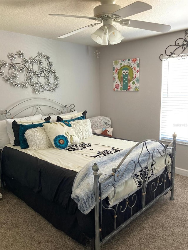 bedroom with ceiling fan, carpet, and a textured ceiling