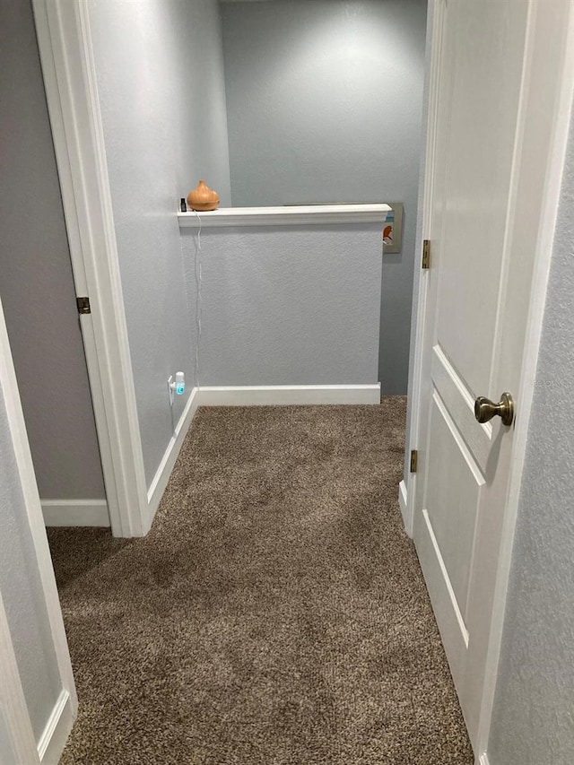 hallway featuring dark colored carpet