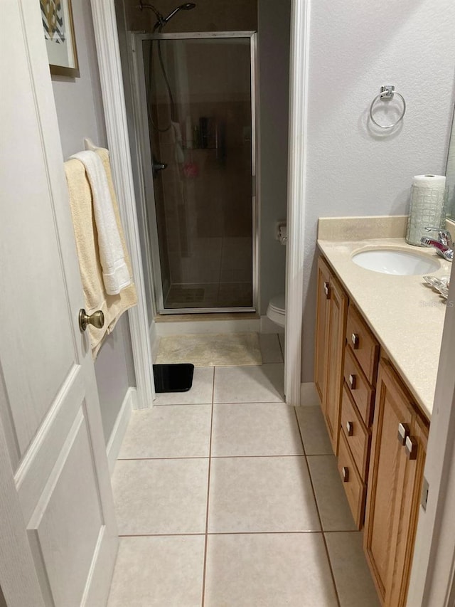 bathroom with vanity, toilet, tile patterned floors, and a shower with shower door