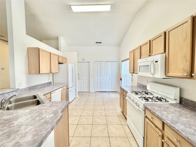 kitchen featuring sink, light tile patterned floors, white appliances, a textured ceiling, and lofted ceiling