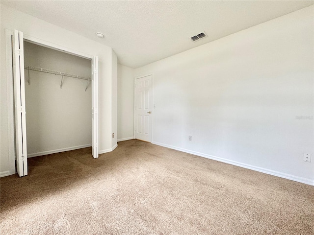 unfurnished bedroom featuring carpet floors, a textured ceiling, and a closet