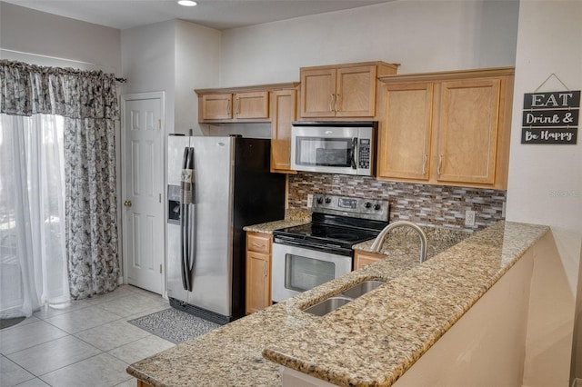 kitchen featuring tasteful backsplash, appliances with stainless steel finishes, light stone counters, and kitchen peninsula