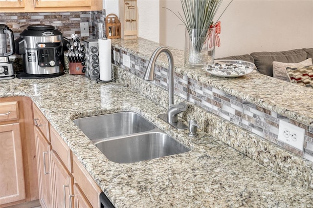 kitchen featuring light stone counters, backsplash, sink, and light brown cabinets