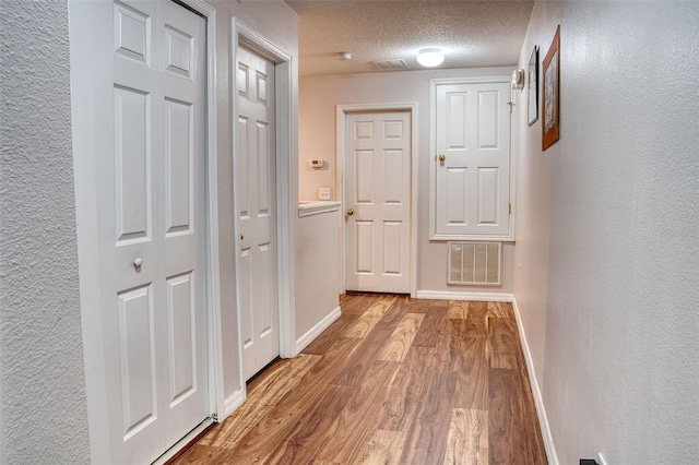 hallway with wood-type flooring and a textured ceiling