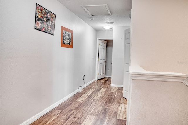 corridor featuring wood-type flooring and a textured ceiling