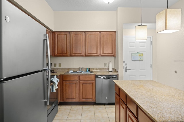 kitchen featuring light stone countertops, appliances with stainless steel finishes, sink, hanging light fixtures, and light tile patterned floors