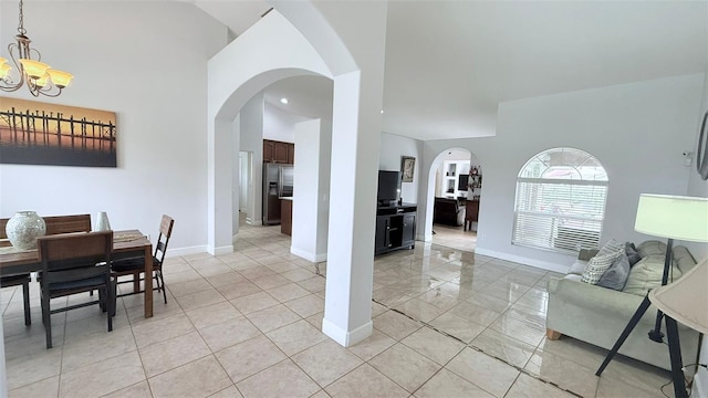 dining room with light tile patterned flooring, a chandelier, and a high ceiling