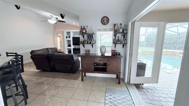 tiled living room featuring ceiling fan, a healthy amount of sunlight, a fireplace, and lofted ceiling