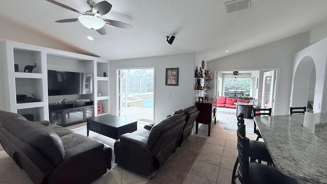 tiled living room with built in shelves, plenty of natural light, a textured ceiling, and lofted ceiling